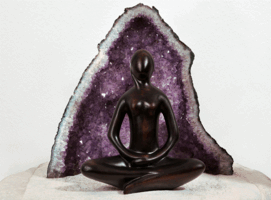 Eine Figur im Lotussitz vor einem Kristallstein